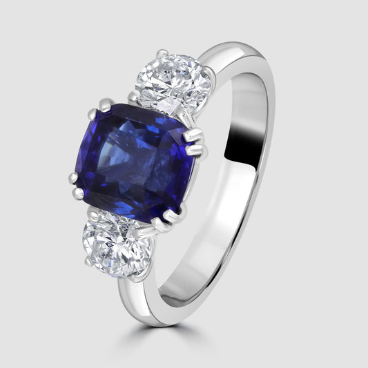 Platinum cushion cut sapphire and diamond three stone ring